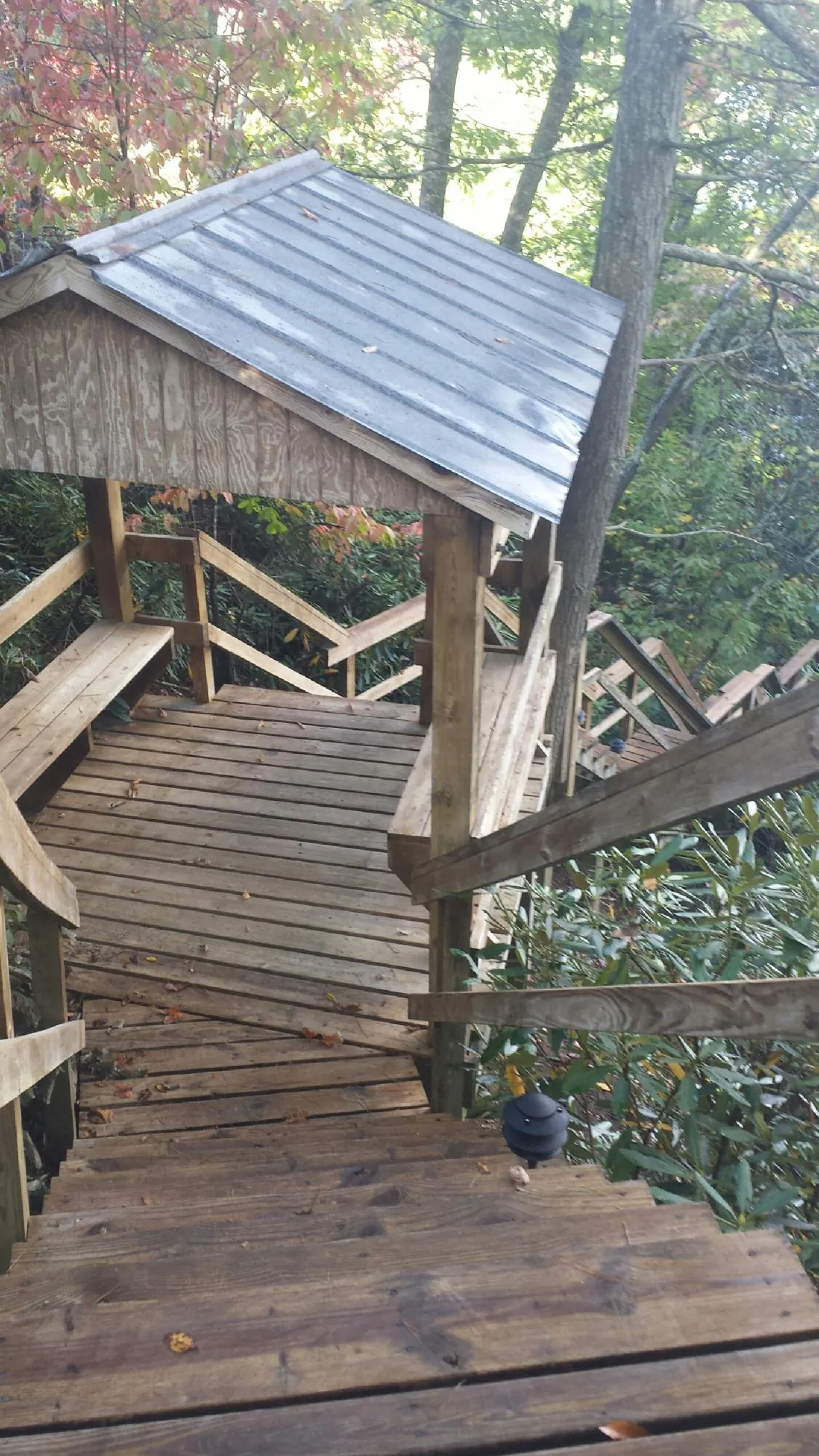 Metal roofed shelter over wooden steps on a wooded walkway — Skylight Repair & Installation work by our crew in Lenox